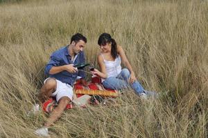 casal feliz desfrutando de piquenique no campo em grama longa foto