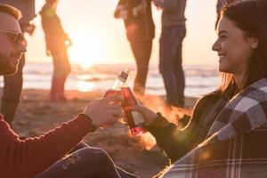 casal curtindo com amigos ao pôr do sol na praia foto