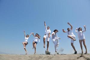 grupo de pessoas felizes se divertir e correr na praia foto