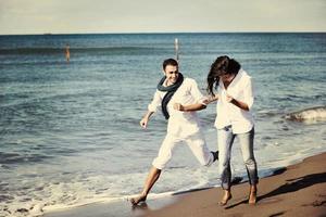 feliz casal jovem se diverte na bela praia foto