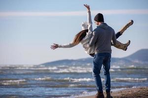 amando o jovem casal em uma praia em dia ensolarado de outono foto