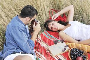 casal feliz desfrutando de piquenique no campo em grama longa foto