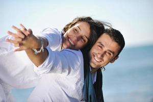 feliz casal jovem se diverte na bela praia foto