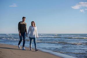 amando o jovem casal em uma praia em dia ensolarado de outono foto