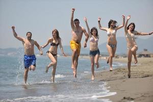 grupo de pessoas felizes se divertir e correr na praia foto