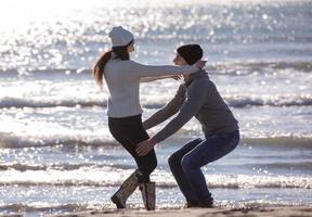 amando o jovem casal em uma praia em dia ensolarado de outono foto