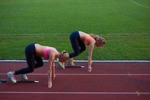 grupo de mulher atleta correndo na pista de atletismo foto