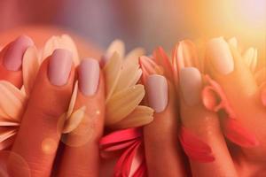 mãos de mulher com manicure segurando flor foto