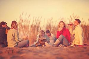 casal curtindo com amigos ao pôr do sol na praia foto