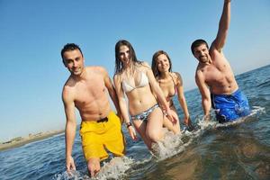 grupo de jovens felizes se divertem na praia foto