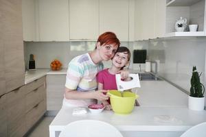 mãe e filha brincando e preparando massa na cozinha. foto