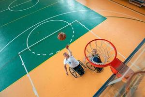 guerra com deficiência ou veteranos de trabalho mistos de raça e idade equipes de basquete em cadeiras de rodas jogando uma partida de treinamento em um ginásio de esportes. conceito de reabilitação e inclusão de pessoas com deficiência. foto