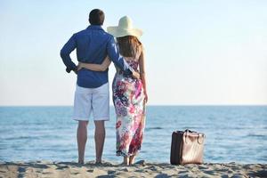 casal na praia com mala de viagem foto