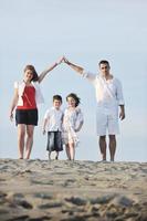 família na praia mostrando sinal de casa foto