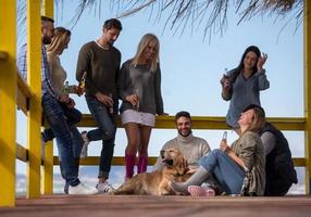 grupo de amigos se divertindo no dia de outono na praia foto