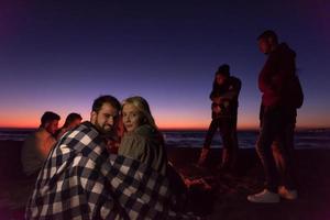 casal curtindo com amigos ao pôr do sol na praia foto