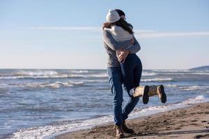 amando o jovem casal em uma praia em dia ensolarado de outono foto