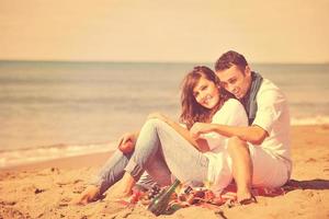 jovem casal desfrutando de piquenique na praia foto