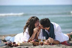 jovem casal desfrutando de piquenique na praia foto