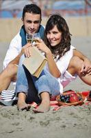 jovem casal desfrutando de piquenique na praia foto