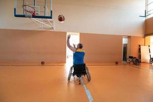 Veteranos de guerra com deficiência equipes de basquete de raça mista e idade em cadeiras de rodas jogando uma partida de treinamento em um ginásio de esportes. conceito de reabilitação e inclusão de pessoas com deficiência foto