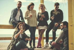 grupo de amigos se divertindo no dia de outono na praia foto