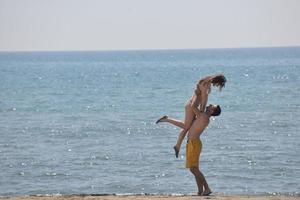 feliz casal jovem se divertir na praia foto
