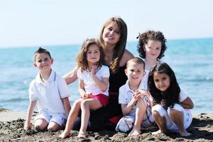 retrato de grupo de crianças com professor na praia foto
