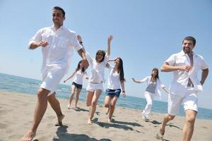 grupo de pessoas felizes se divertir e correr na praia foto