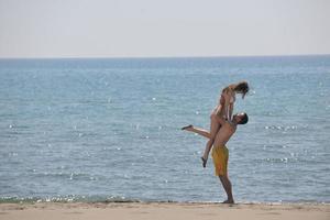 feliz casal jovem se divertir na praia foto