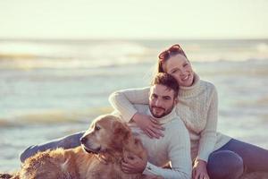 casal com cachorro aproveitando o tempo na praia foto