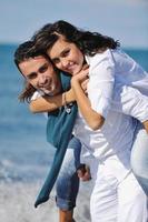 feliz casal jovem se diverte na bela praia foto