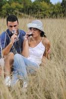 casal feliz desfrutando de piquenique no campo em grama longa foto