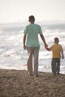 pai e filho caminhando na praia foto