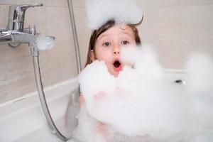 menina no banho brincando com espuma foto