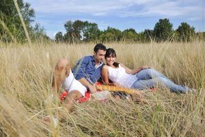 casal feliz desfrutando de piquenique no campo em grama longa foto