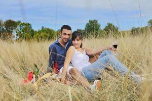 casal feliz desfrutando de piquenique no campo em grama longa foto