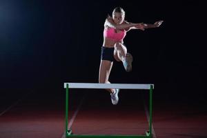 atleta de mulher pulando sobre obstáculos foto