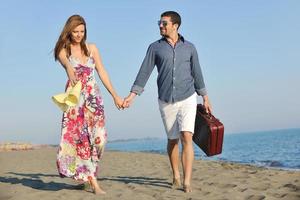 casal na praia com mala de viagem foto