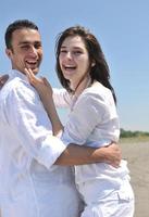 feliz casal jovem se divertir na praia foto