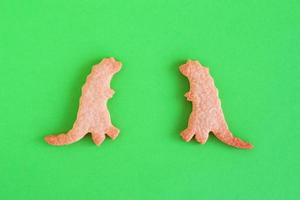 biscoitos caseiros de shortbread em formas de dinossauros em fundo verde, vista superior. foto
