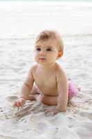 sincero retrato de adorável menina na areia na praia no fundo do mar. desenvolvimento sensorial para crianças ao ar livre. foto