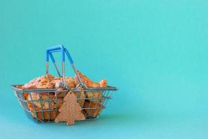 cesta de compras com cantucci de biscoitos de amêndoa italianos tradicionais decorados árvore de natal de madeira sobre fundo azul. decoração mínima para o conceito de natal. foto