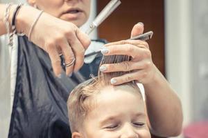 criança pequena durante o corte de cabelo na barbearia. foto