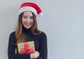 mulher segurando um presente com chapéu de Papai Noel foto