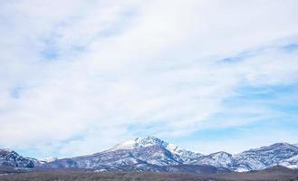 montanhas cobertas de neve com céu azul e nuvens foto