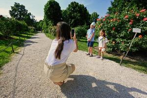 mãe tira fotos de crianças no jardim em seu telefone.