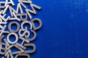 maquete plana de caracteres do alfabeto de metal prateado no fundo da placa pintada azul com copyspace.