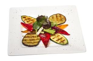 legumes grelhados no prato e fundo branco foto