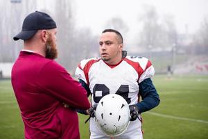 jogador de futebol americano discutindo estratégia com treinador foto